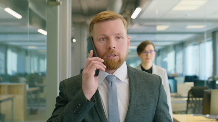 Uomo d'affari che cammina in ufficio e parla al telefono