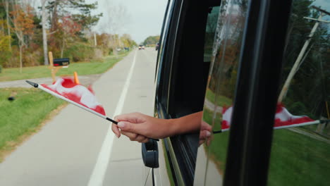 Hand-Hält-Kanadische-Flagge-Aus-Dem-Autofenster