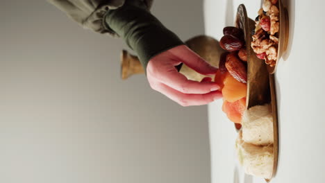 hand reaching for dried fruit and sweets on a brass tray.
