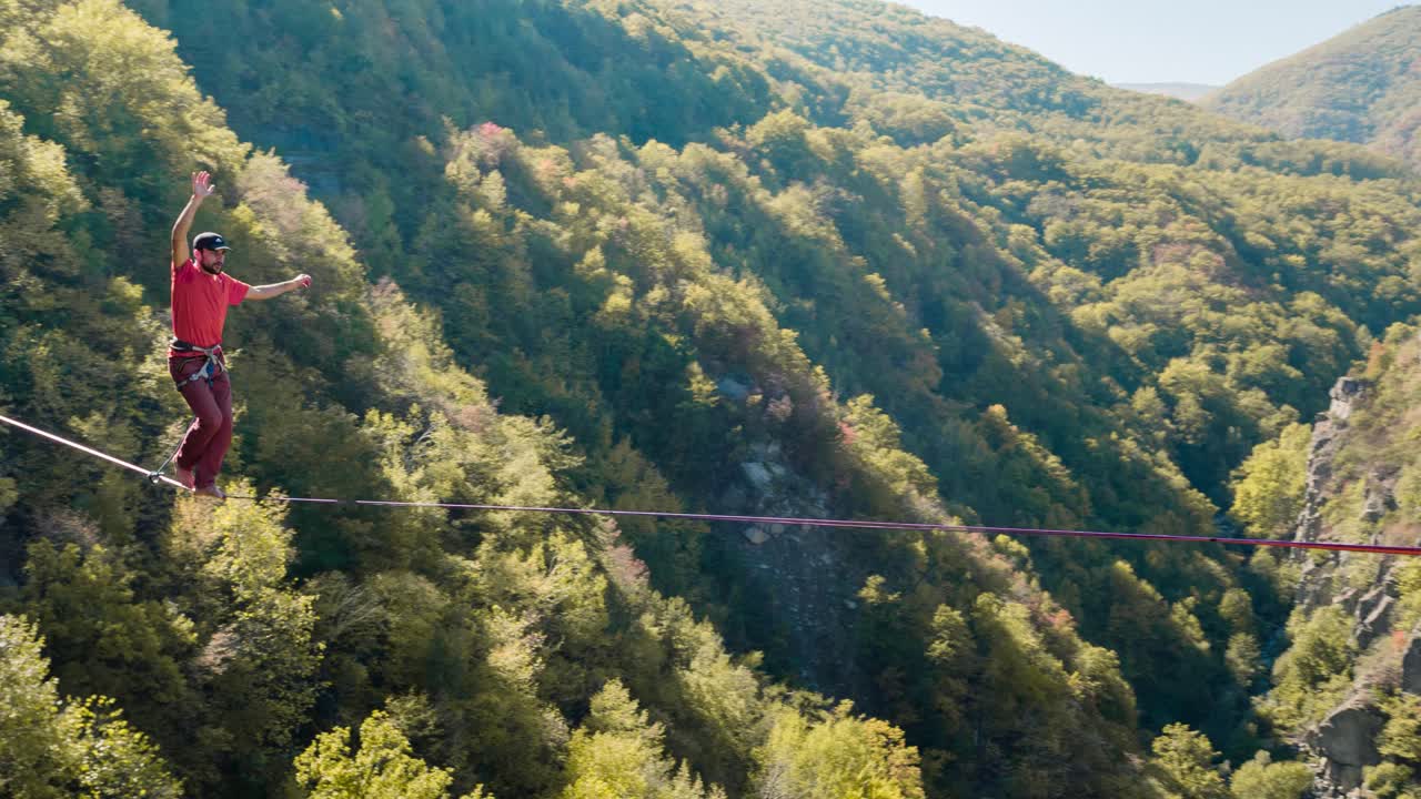 Uomo che fa slacklining attraverso una valle di montagna