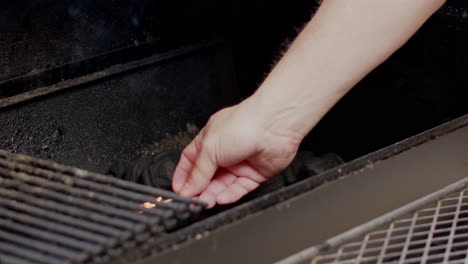 fósforos colocados en un lecho de carbón y encendiendo un fuego en un fumador de foso de barbacoa