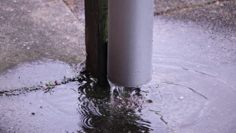 rain running through pipe, then flows out onto tiles.