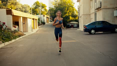 una chica deportiva en un uniforme deportivo de verano corre a lo largo de los patios en la calle por la mañana