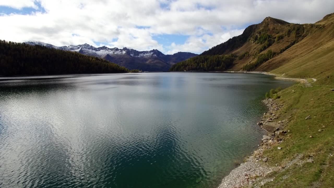 vista aérea del lago de montaña en suiza durante el otoño con bosque de pinos de colores, día de otoño nublado con montañas nevadas, lago ritom