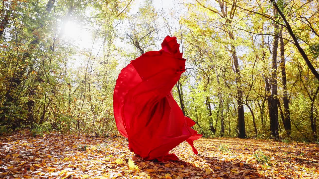 A Majestic Woman in a Flowing Red Dress Dancing Gracefully Among Vibrant Autumn Leaves in a Sunlit Forest, Capturing the Essence of Nature's Beauty