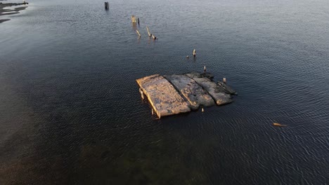 the remnants of a cement dock off the shore of muskegon lake in evening