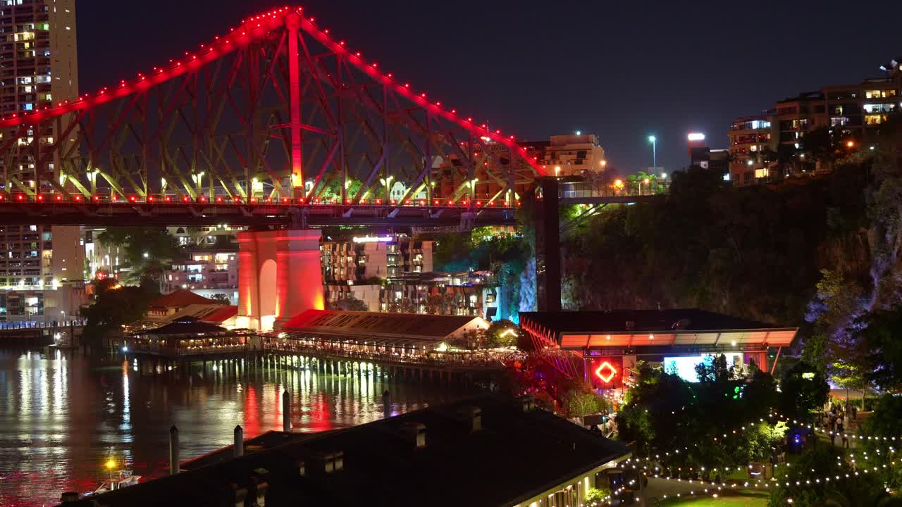 Howard Smith Wharves, the beating heart of Brisbane's entertainment scene, time-lapse shot of vibrant nightlife of Brisbane city with iconic Story bridge illuminated in red.