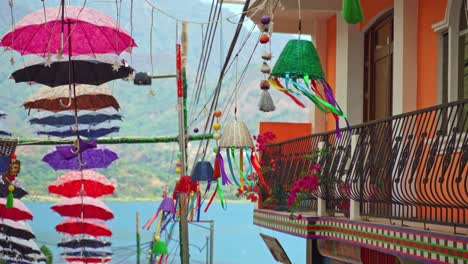 decoraciones coloridas, paraguas y cestas colgando sobre una calle de mercado en san juan, lago atitlan, guatemala