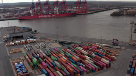 Reveal-of-docked-cargo-shipping-boat-in-industrial-port-with-cargo-containers-in-Hamburg,-Germany