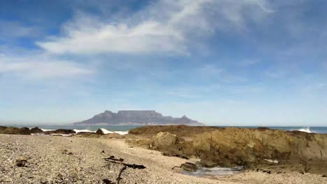 caminando por una playa pedregosa junto a la montaña de la mesa de ciudad del cabo
