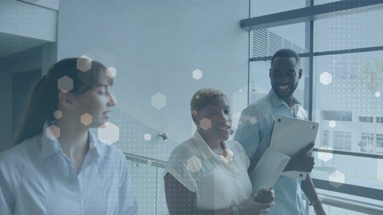 Center woman tapping tablet and showing hex overlays while business team walking, reviewing project