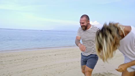 pareja feliz corriendo en la playa en un día soleado