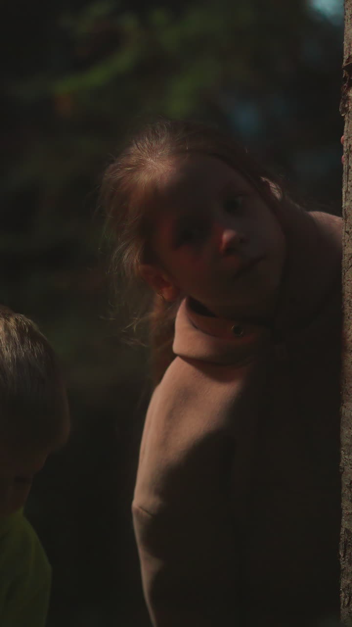 niños se esconden detrás de un árbol en el bosque de la noche. niño y niña asustados perdidos en un parque salvaje por la noche. niños en edad preescolar amenazados por la soledad y la oscuridad