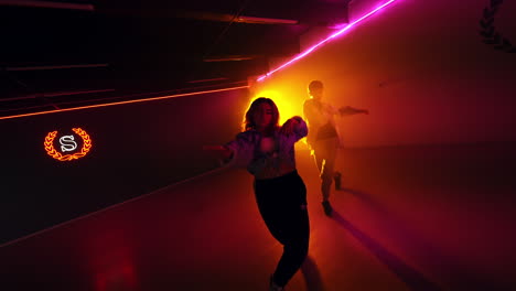 couple of dancers move energetically. young people dance hip hop in the studio in yellow light.