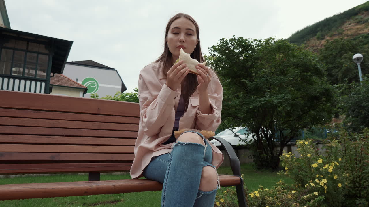 야외에서 샌드위치를 먹는 여자