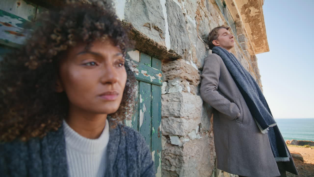 Romantic models posing rocks looking distance at ocean closeup. Serious couple