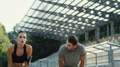 pareja de jóvenes corredores corriendo en el estadio, luego se detienen para descansar y mirar la cámara