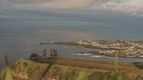 wide view of town by coast at the azores and open ocean, handheld pan