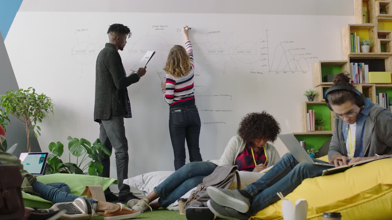 eine junge gruppe von wirtschaftsstudenten studiert zusammen, arbeitet an einem projekt, unterrichtet einen praktikanten, teilt ideen in einem bunten, multiethnischen büro.