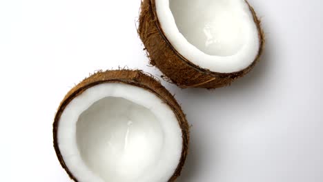 ripe tropical coconut split in two halves rotating on a white background. tropical fruits, loopable