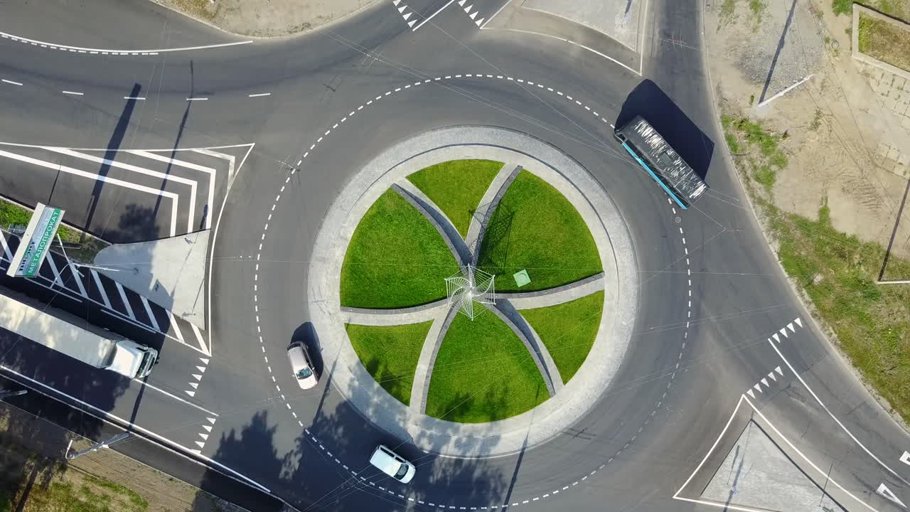 City Traffic At Roundabout. Flying above huge roundabout full of cars and trucks at rush hour
