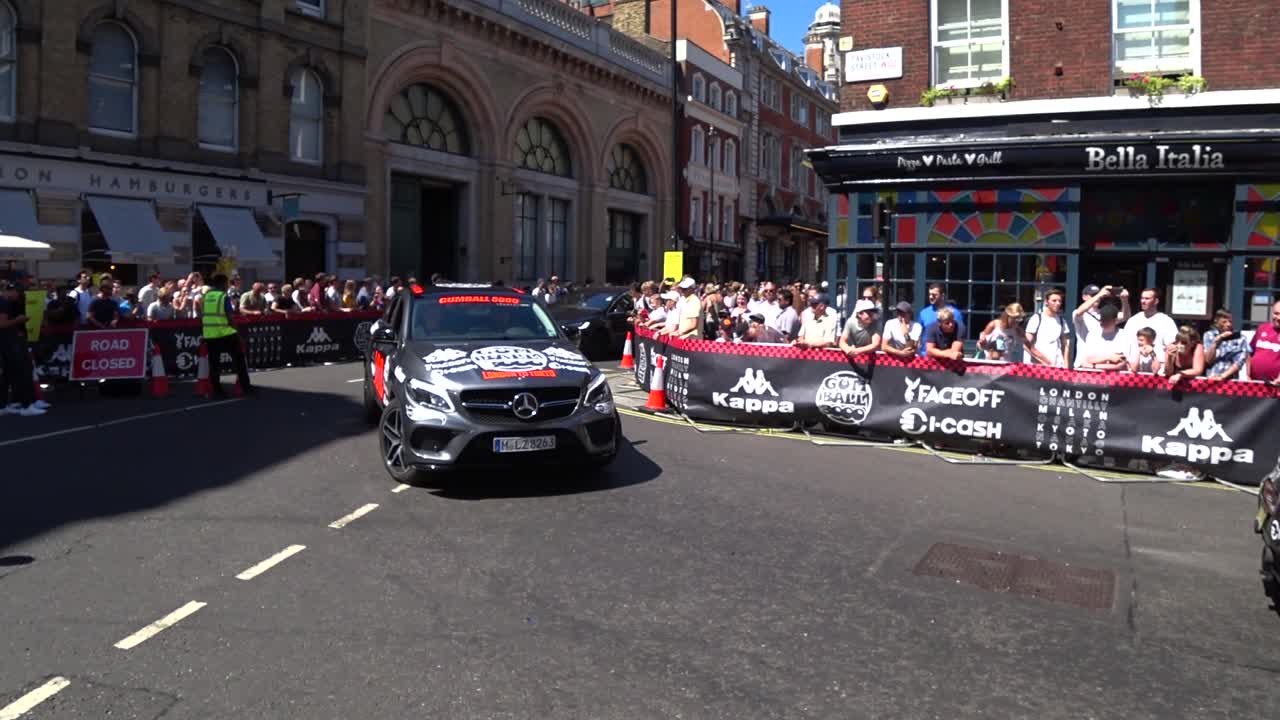 Line of luxury cars driving on london road during Gumball 3000 Event in London. Static shot.