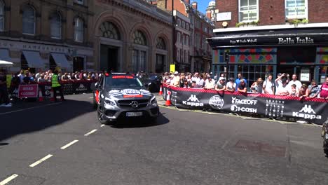 line of luxury cars driving on london road during gumball 3000 event in london. static shot.