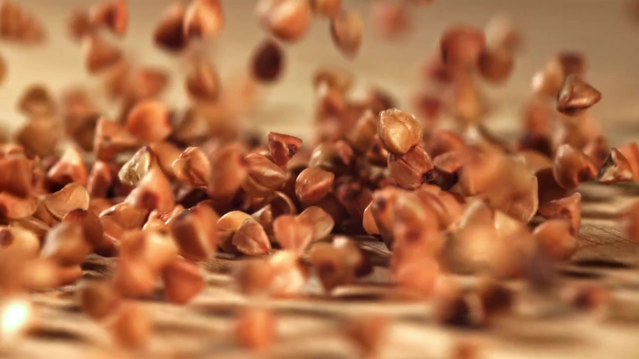 Raw Buckwheat Grains Falling in Slow Motion onto a Wooden Surface