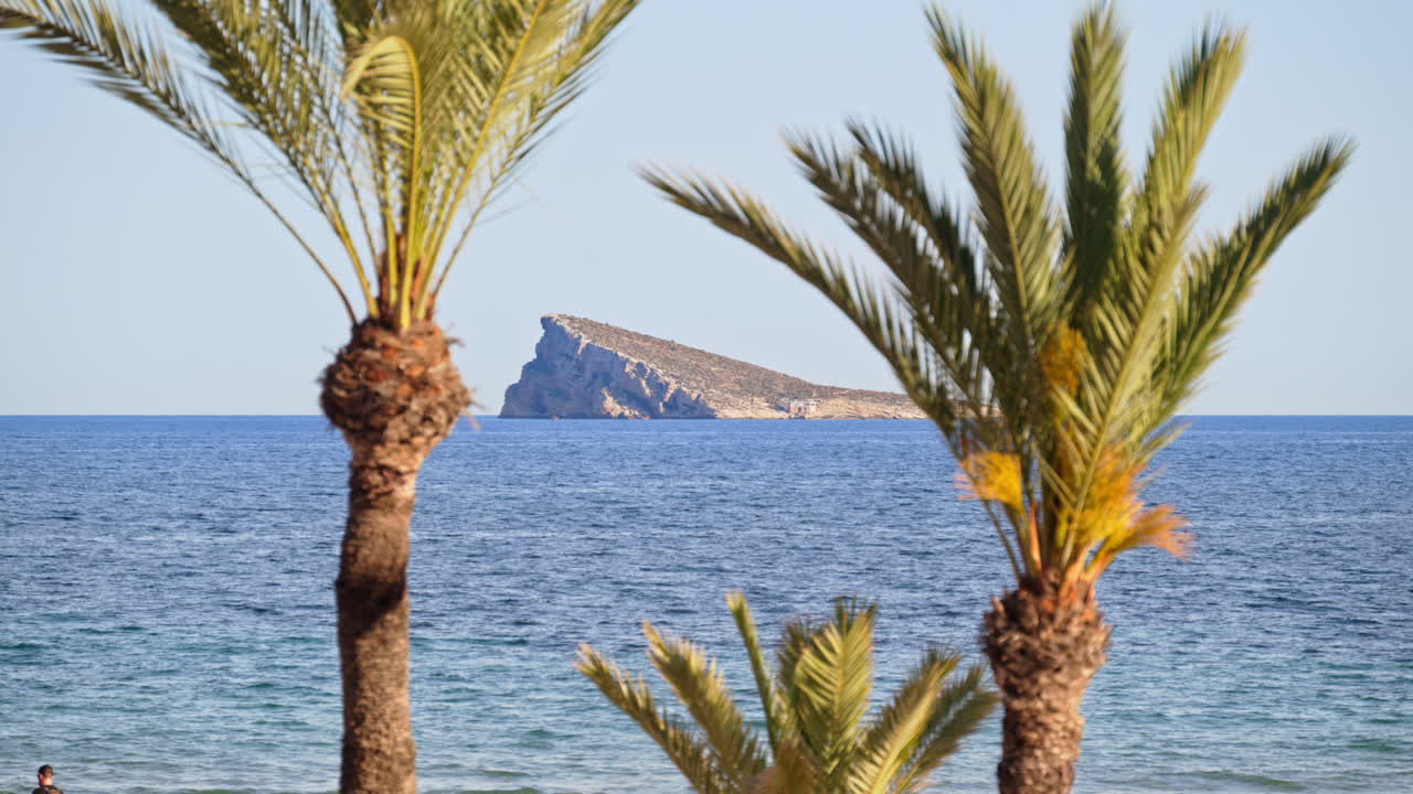 Benidorm Island framed by palms, seen from the seafront promenade in Benidorm, Alicante