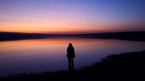 silhouette of a person at sunset on a calm lake