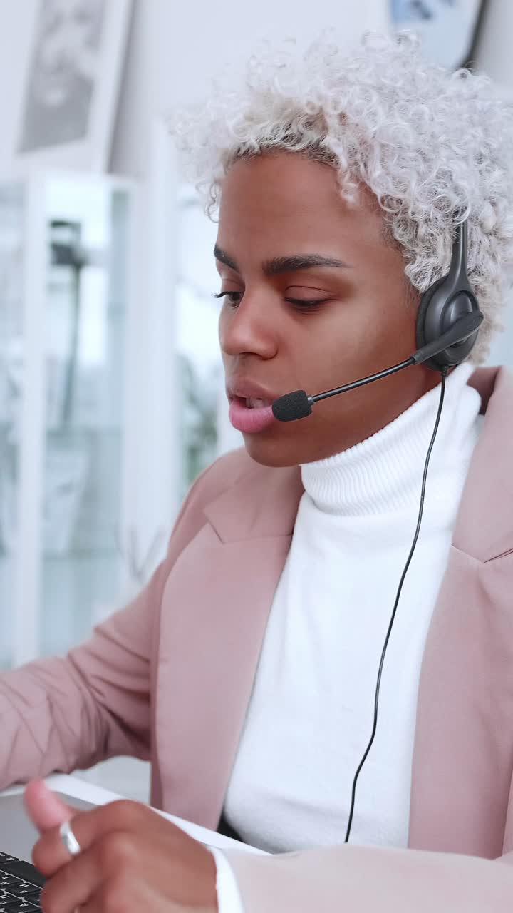 Donna che lavora in ufficio con cuffie e computer durante il giorno