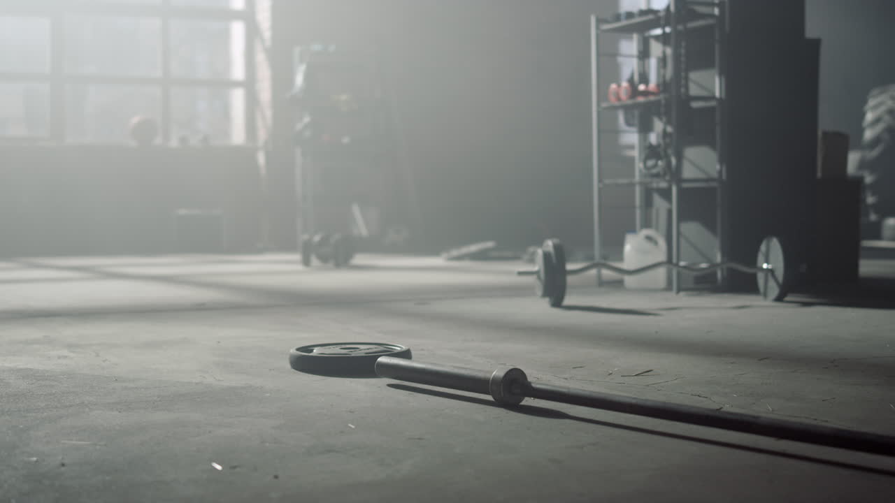 바닥에 누워있는 무거운 무게를 가진 바벨. 스포츠 장비와 함께 체육관 내부