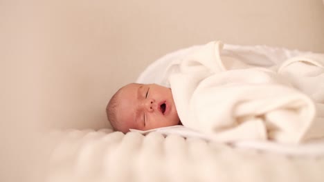 un lindo bebé recién nacido acostado en un sofá blanco suave cubierto con una manta durmiendo lentamente