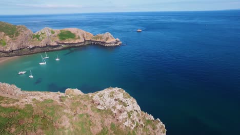 Drohnenaufnahmen-Des-Türkisfarbenen-Wassers-Einer-Bucht,-In-Der-Fünf-Segelboote-An-Einem-Sonnigen-Tag-Auf-Der-Insel-Sark,-Kanalinseln,-Festgemacht-Sind