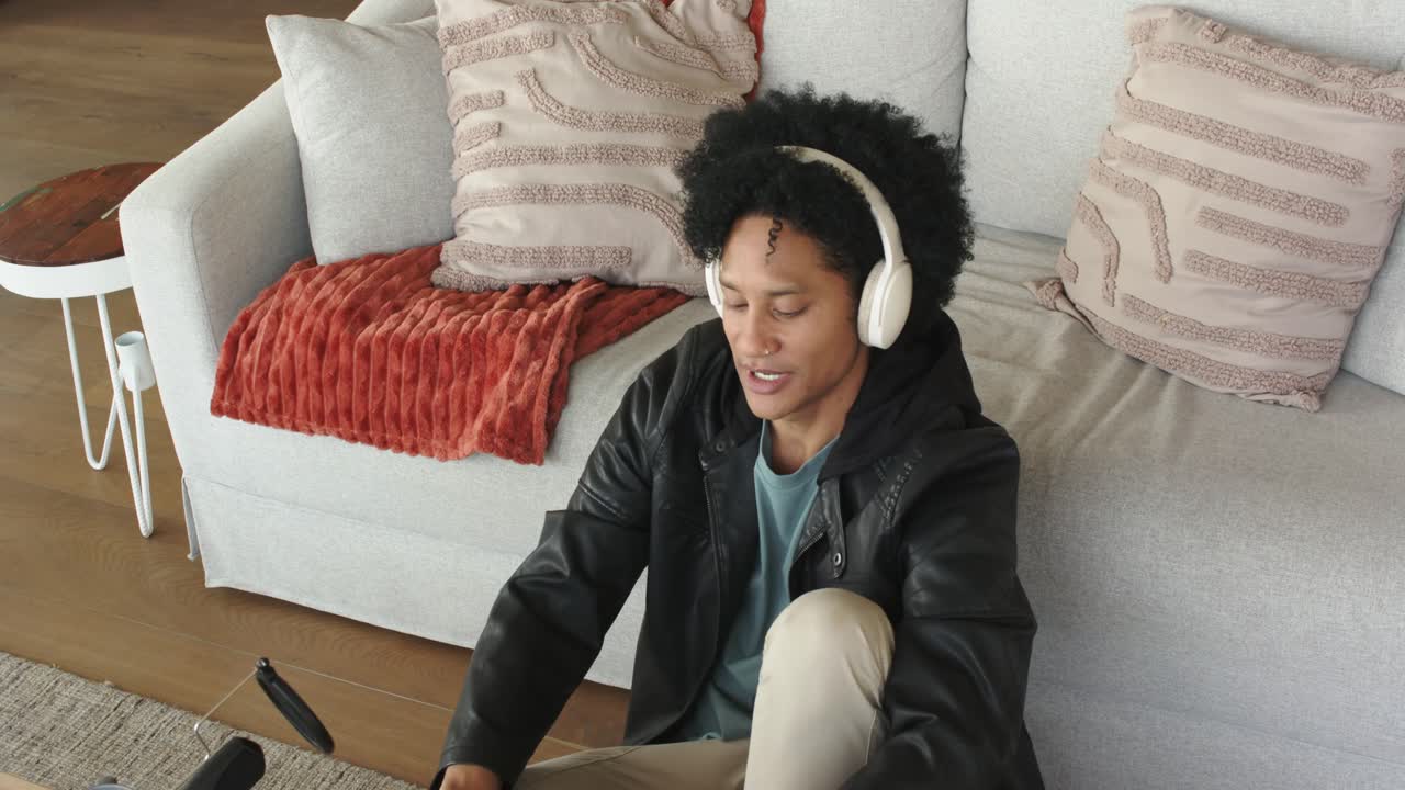 Uomo afroamericano che avvia un podcast da casa, parla al microfono, indossa cuffie e digita appunti