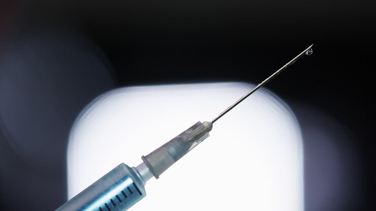Handheld close up of syringe with droplet