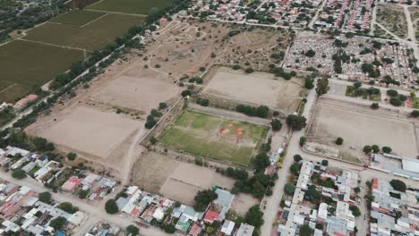 Aerial-drone-shot-of-an-empty-soccer-or-football-field-surrounded-by-resedential-houses-of-cafayate-town-in-Argentina-south-america