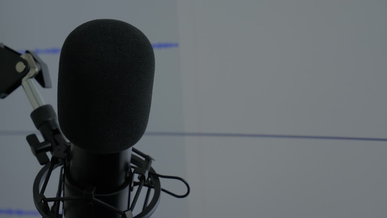 micrófono negro grabando audio en pantalla digital en segundo plano, de cerca