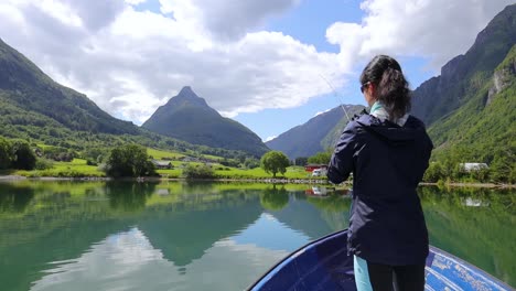 woman on the boat catches a fish on spinning in norway.