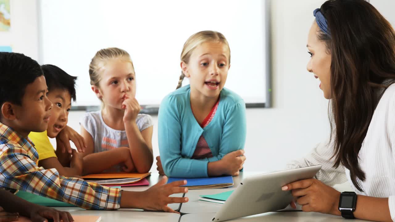 Teacher teaching school kids on digital tablet in classroom