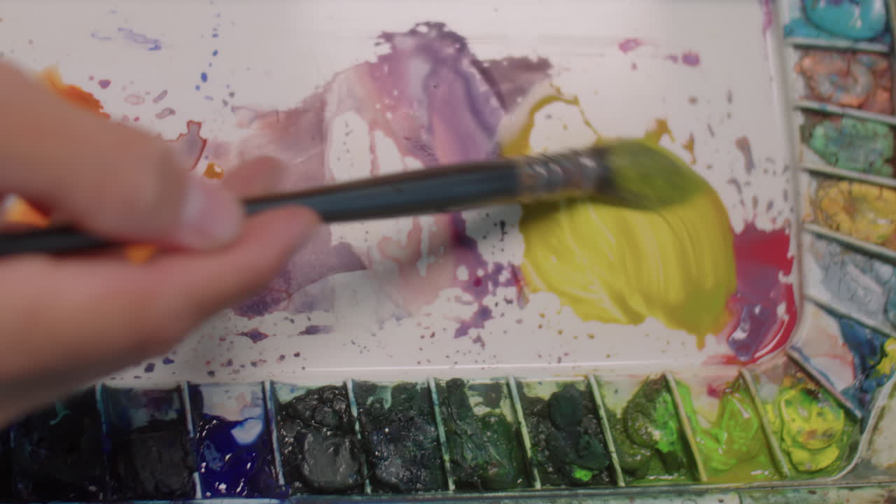 Hand of Artist Mixing Colors on Palette with Brush
