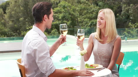 smiling couple drinking wine poolside