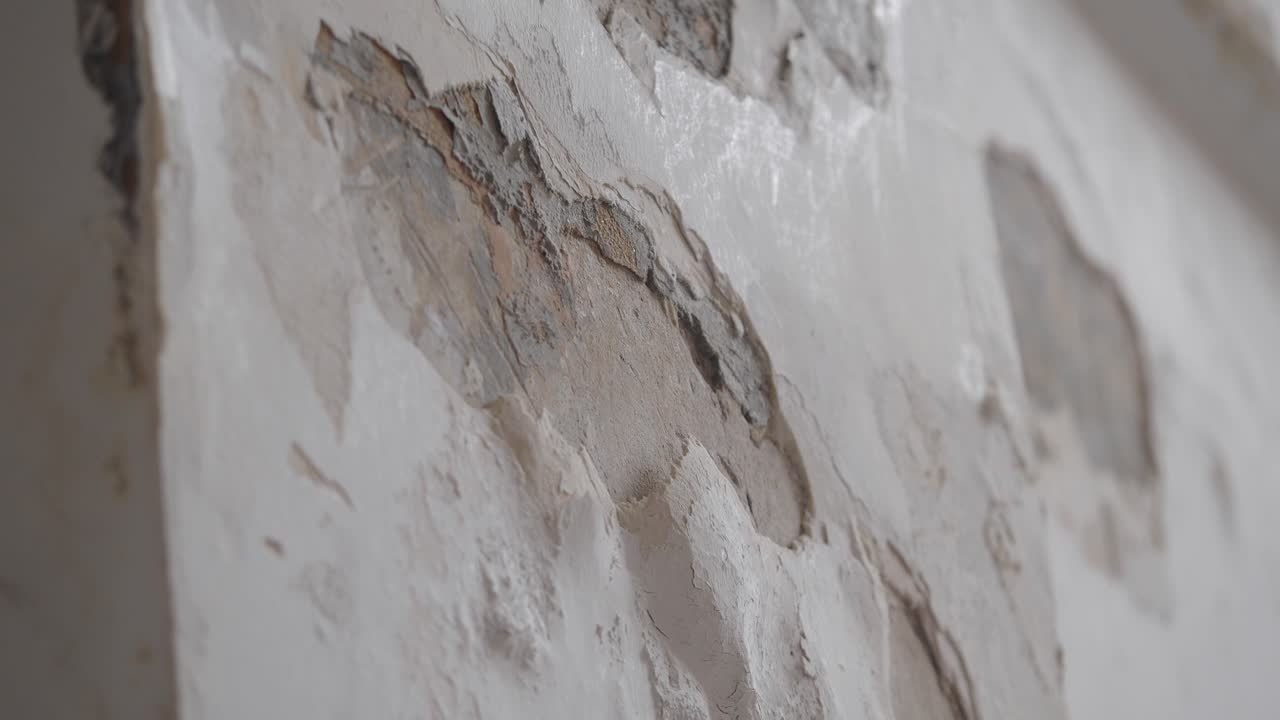Primo piano di pittura scrostata e intonaco danneggiato su un vecchio muro