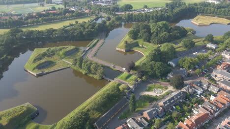 aerial of traffic driving over small bridge in a beautiful, green landscape in the netherlands