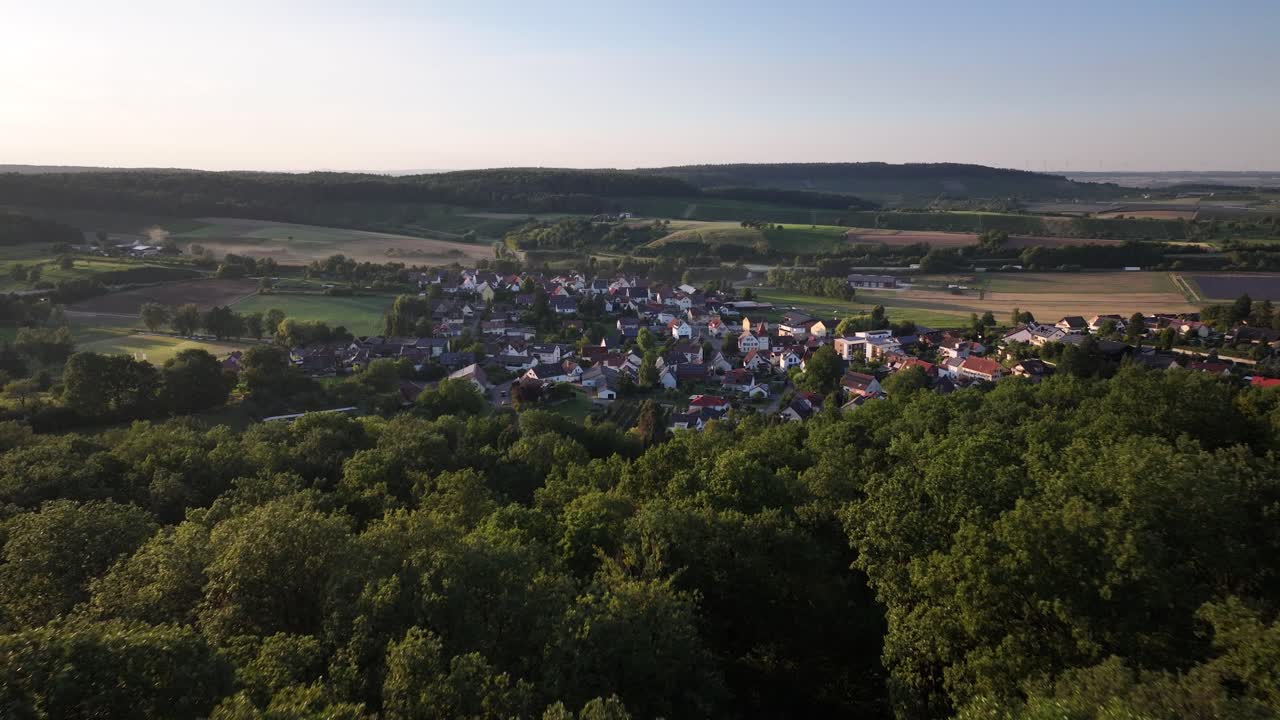 Luftfoto av en europeisk landsby som dukker opp bak en skog