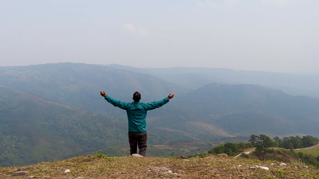 hombre disfrutando de la naturaleza en la cima de la colina con el fondo de la furia de la montaña brumosa desde un video de ángulo plano tomado en nongjrong meghalaya india