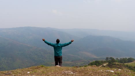 Mann,-Der-Die-Natur-Auf-Einem-Hügel-Mit-Nebligem-Bergwuthintergrund-Aus-Einem-Flachen-Winkelvideo-Genießt,-Wird-In-Nongjrong-Meghalaya,-Indien,-Aufgenommen