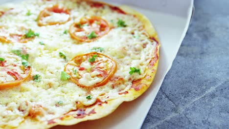 pizza al horno con aderezos de tomate cereza en la caja de entrega
