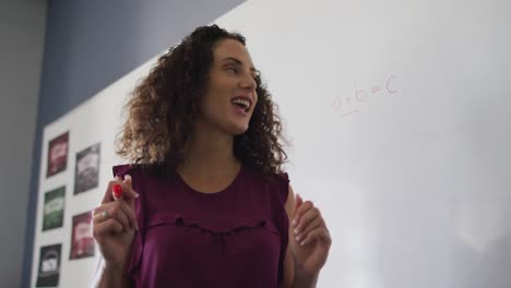 video of happy caucasian female teacher standing in classroom and explaining lesson