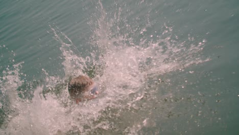 vista de cerca de un niño caucásico corre saltando al lago desde el muelle de madera